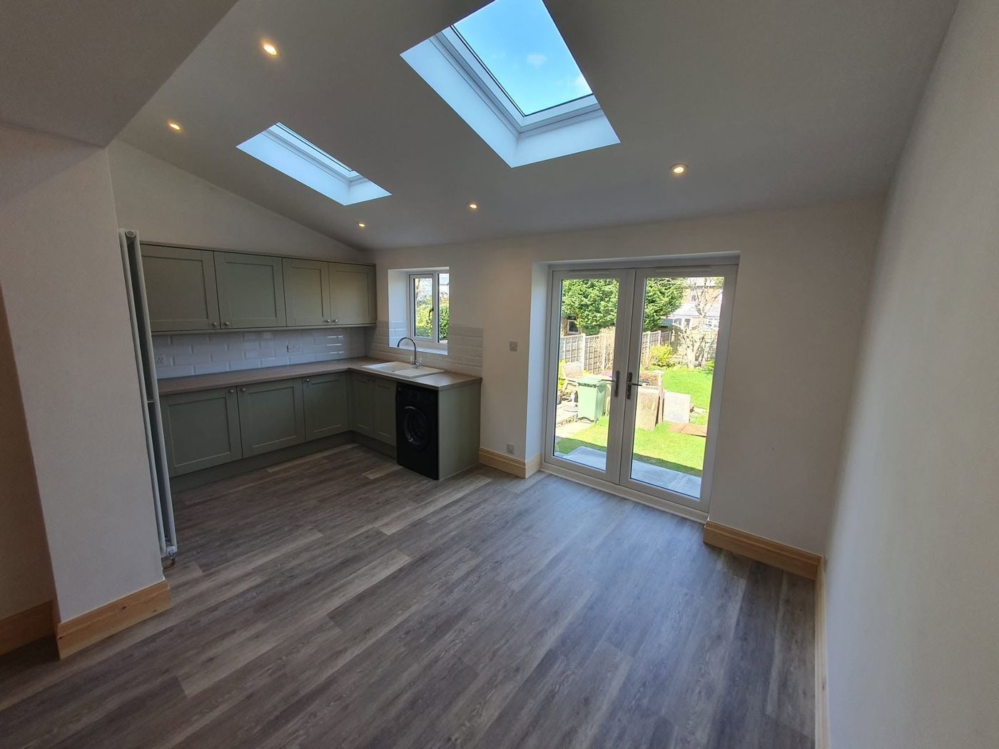 Sage green shaker kitchen in a new extension with vaulted ceiling and skylights