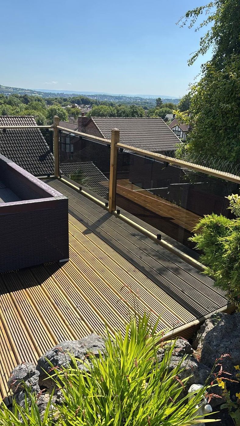Raised timber deck with glass balustrade overlooking countryside, by PJB
